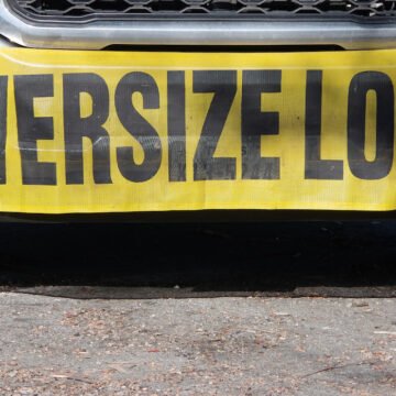 Driver in push truck flips while aiding oversize load