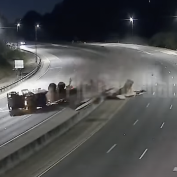 Arkansas DOT cams catch flatbed truck rolling on a curve, spilling load all over interstate