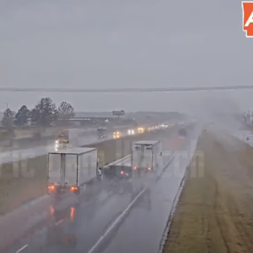 Four wheeler bounces off tractor trailers in rainy traffic cam