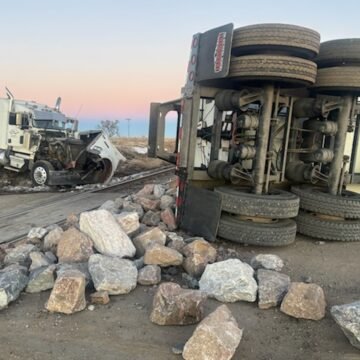 Semi truck and train damaged in collision involving trailer full of rocks
