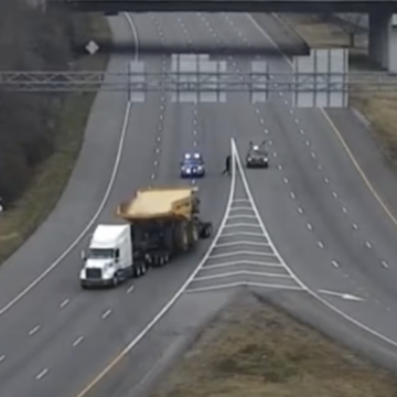 Trucker with oversize load avoids striking railroad bridge by reversing onto on-ramp