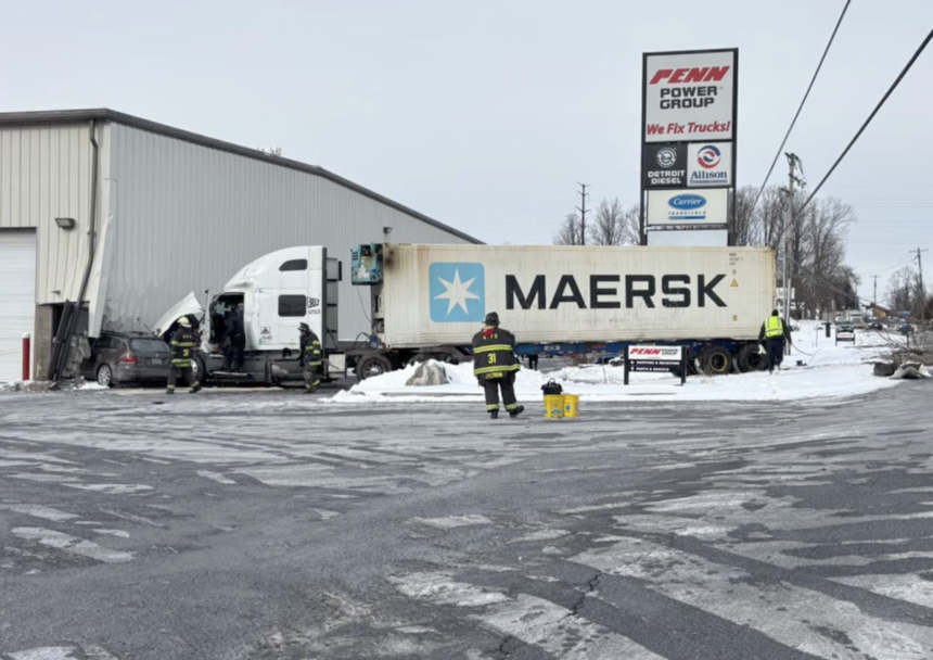 Tractor trailer pushes car into side of truck repair shop